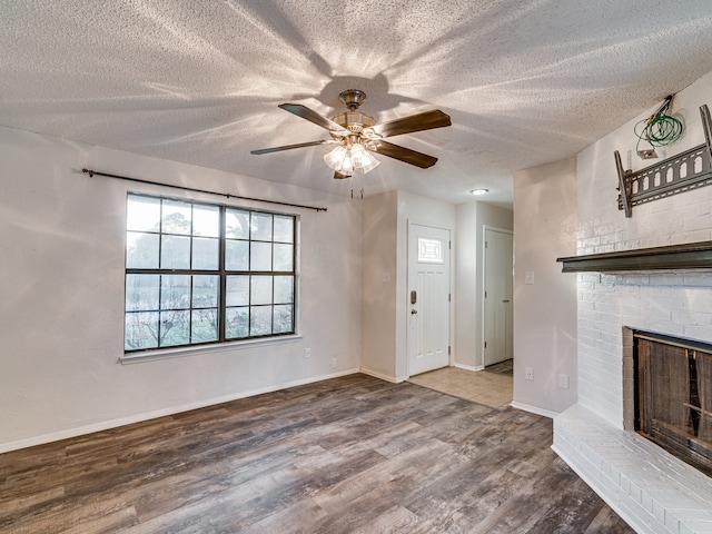 5005 Drew Ct, Arlington, TX 76017 - unfurnished living room with a textured ceiling, a ceiling fan, a brick fireplace, and wood finished floors