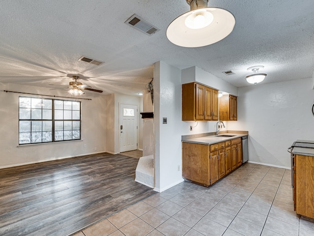 5005 Drew Ct, Arlington, TX 76017 - kitchen with ceiling fan, a sink, a textured ceiling, brown cabinetry, and visible vents