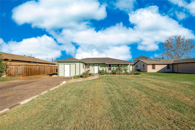 view of front of home featuring an outdoor structure, a front lawn, fence, driveway, and a storage shed