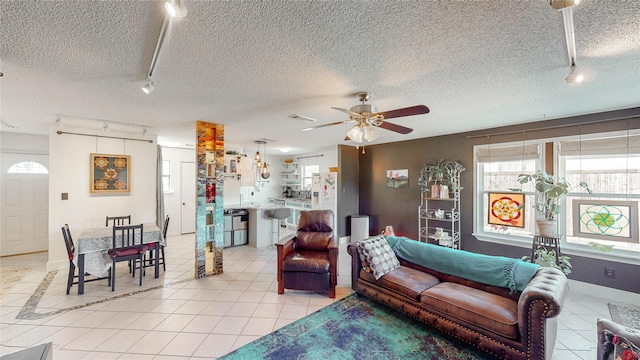 living area with rail lighting, a textured ceiling, ceiling fan, and light tile patterned flooring