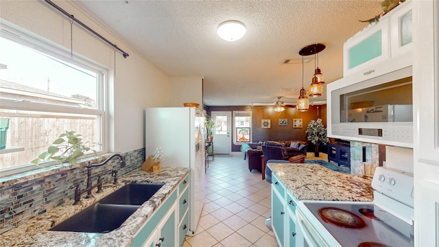 kitchen with white appliances, a textured ceiling, a sink, light tile patterned floors, and hanging light fixtures