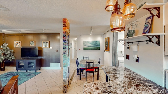 tiled dining space with a textured ceiling, visible vents, and track lighting