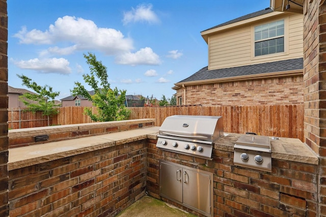 view of patio featuring a fenced backyard, a grill, and an outdoor kitchen