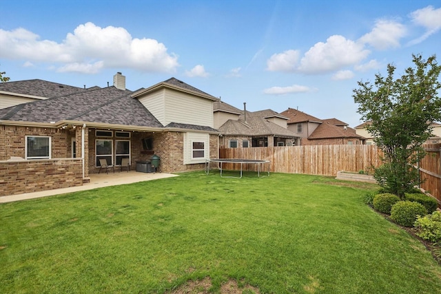 view of yard featuring a patio, a fenced backyard, and a trampoline