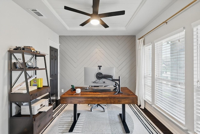 home office with visible vents, a ceiling fan, and a raised ceiling