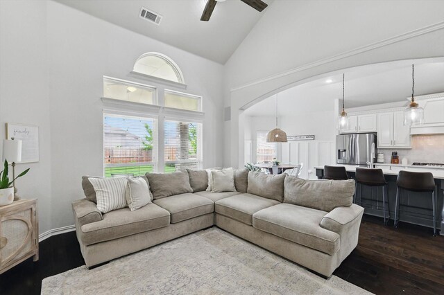 living room featuring visible vents, high vaulted ceiling, arched walkways, a ceiling fan, and dark wood finished floors