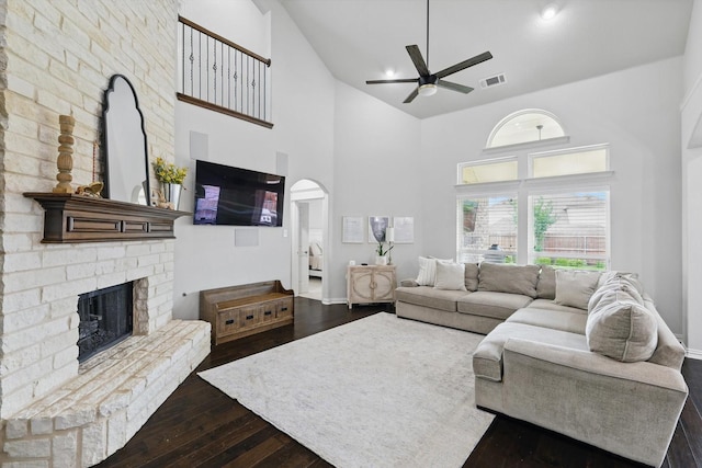 living area featuring ceiling fan, a fireplace, high vaulted ceiling, visible vents, and dark wood-style floors