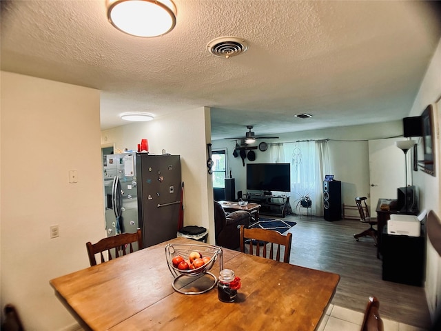 dining area featuring visible vents, a ceiling fan, a textured ceiling, and wood finished floors
