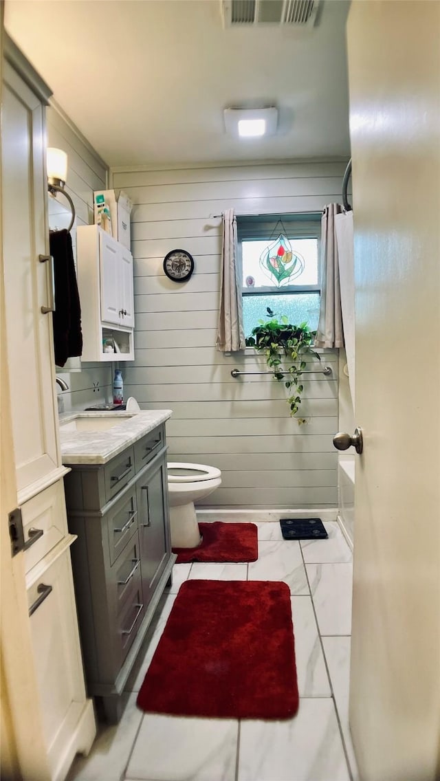 bathroom featuring wooden walls, toilet, visible vents, and vanity