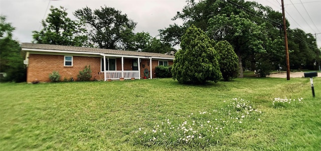 rear view of property with covered porch, brick siding, and a yard