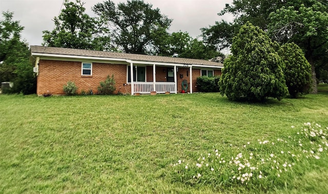 view of front of home featuring brick siding, covered porch, and a front yard