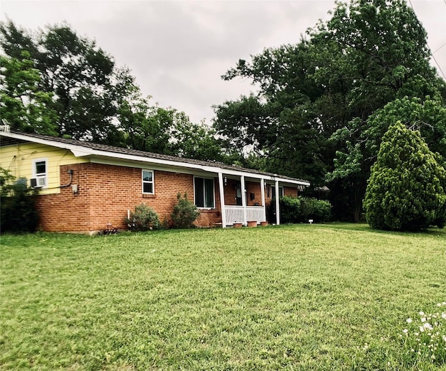 back of house with a porch, a lawn, cooling unit, and brick siding
