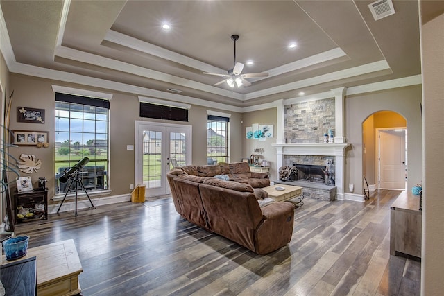 living room with arched walkways, a ceiling fan, wood finished floors, a tray ceiling, and visible vents