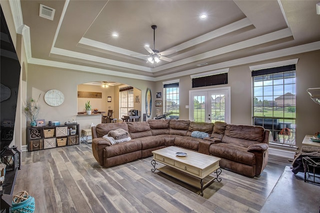 living room featuring arched walkways, a ceiling fan, visible vents, and a wealth of natural light