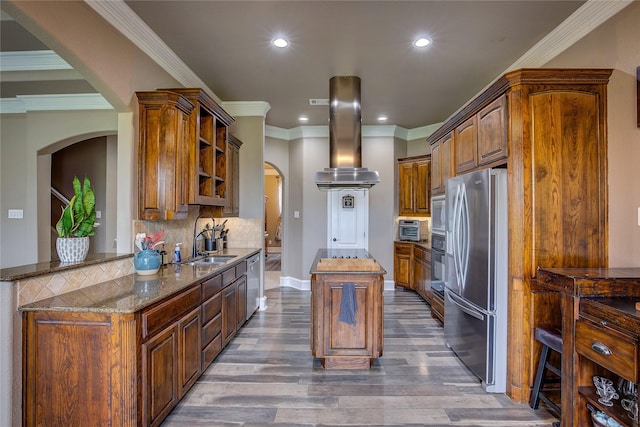 kitchen featuring appliances with stainless steel finishes, a center island, arched walkways, open shelves, and a sink