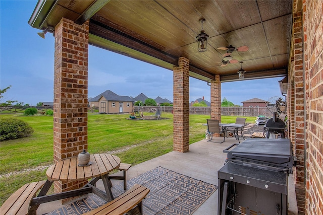 view of patio / terrace with ceiling fan, fence, and an outbuilding