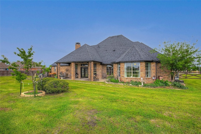 back of property featuring a lawn, a chimney, a patio area, and brick siding