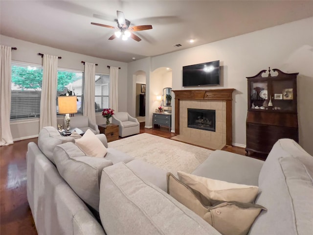 living area with arched walkways, a ceiling fan, wood finished floors, and visible vents