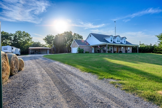 country-style home featuring a porch, driveway, a front lawn, and brick siding