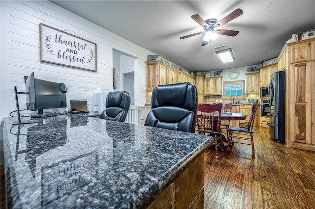 office area with ceiling fan, dark wood-type flooring, wood walls, and visible vents