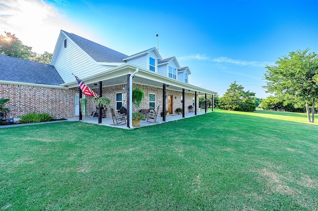 exterior space featuring a lawn, a patio, and brick siding
