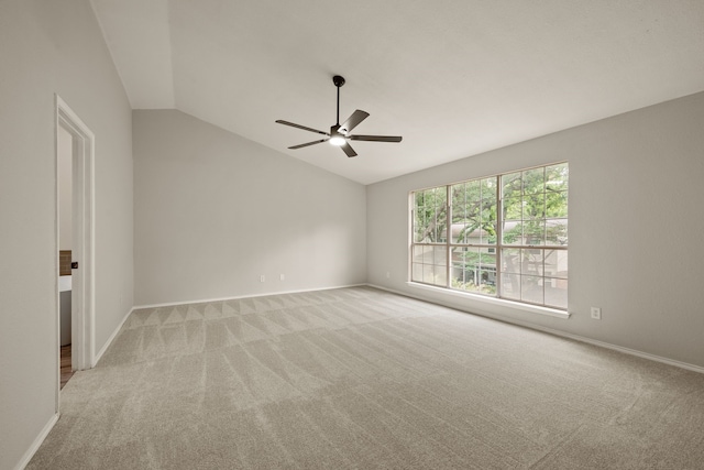 empty room featuring baseboards, a ceiling fan, vaulted ceiling, and light colored carpet