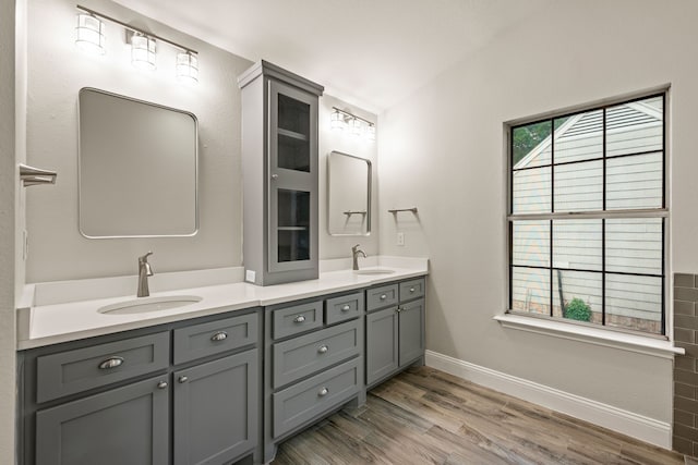 bathroom with double vanity, a sink, baseboards, and wood finished floors