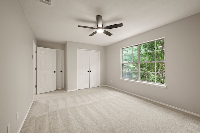 unfurnished bedroom featuring baseboards, visible vents, a closet, and light colored carpet