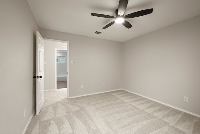 empty room with baseboards, light carpet, a ceiling fan, and visible vents