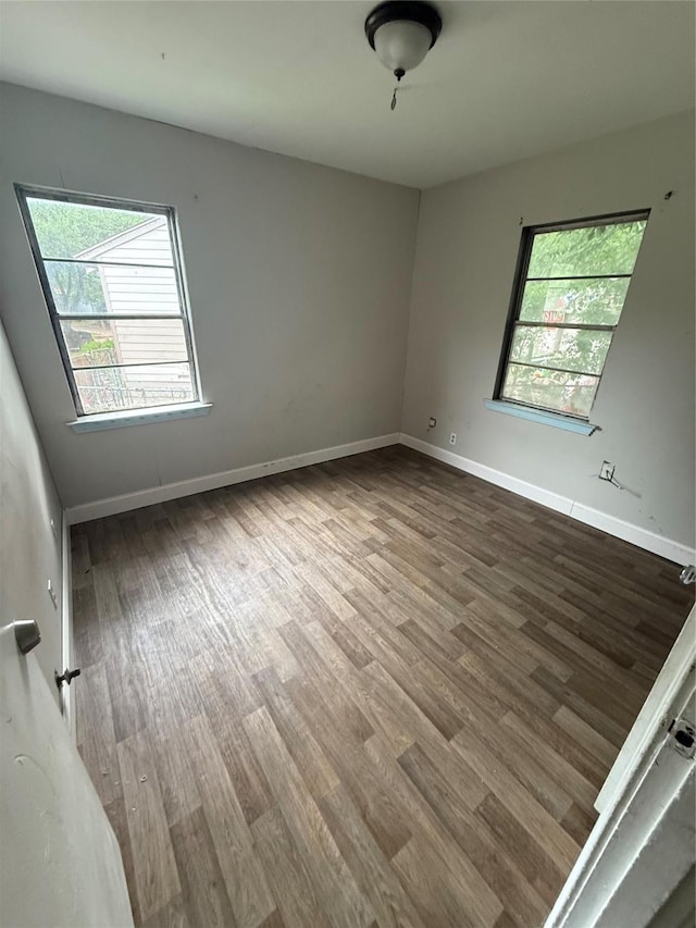 unfurnished room with a healthy amount of sunlight, baseboards, and wood finished floors