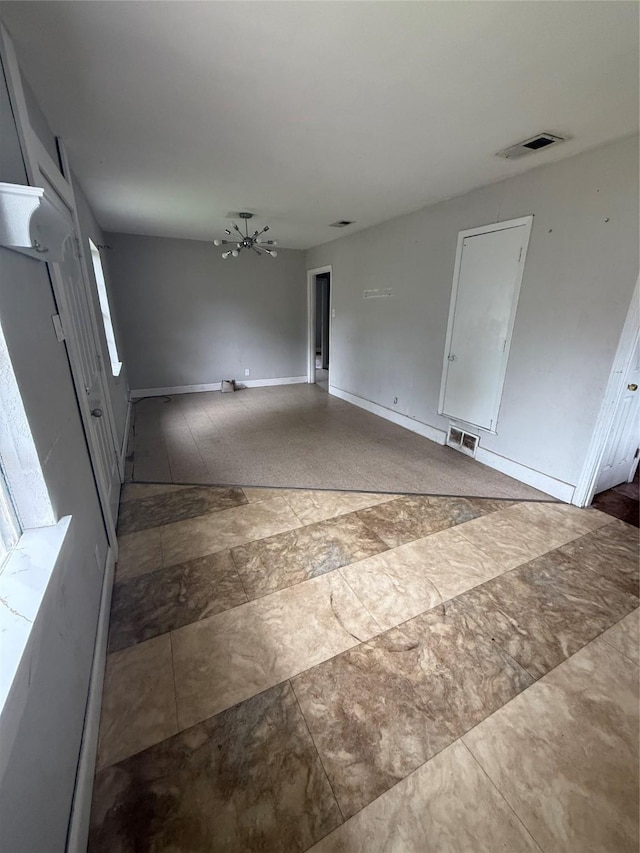 interior space with visible vents, baseboards, and a notable chandelier