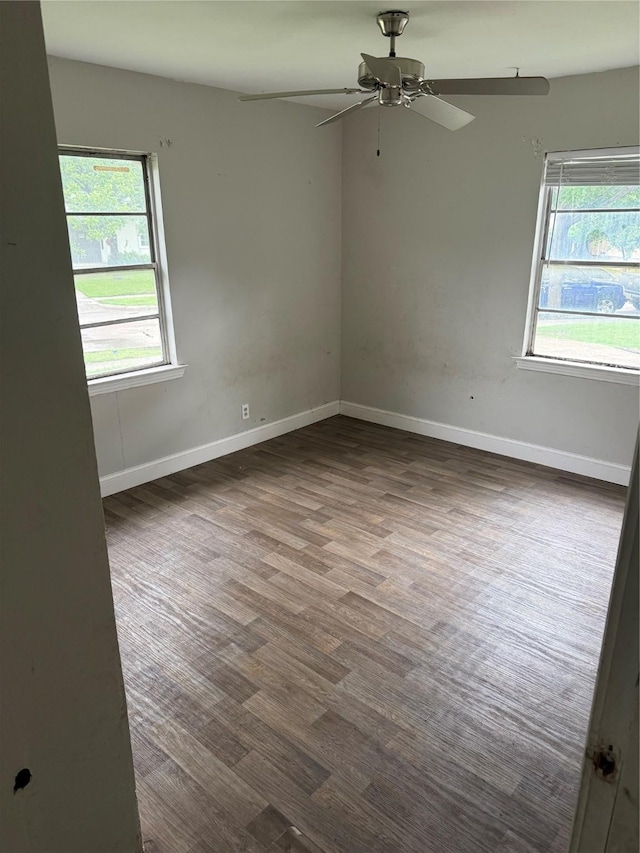 spare room featuring plenty of natural light, a ceiling fan, dark wood finished floors, and baseboards