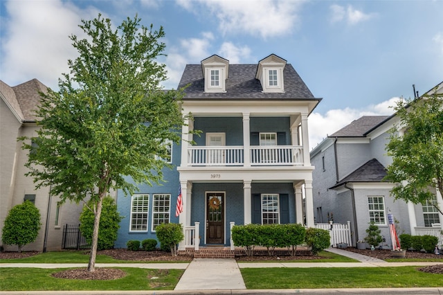 neoclassical / greek revival house featuring brick siding, fence, a balcony, and covered porch