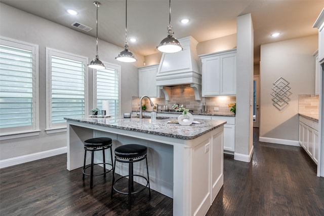 kitchen with a sink, dark wood finished floors, baseboards, decorative backsplash, and visible vents