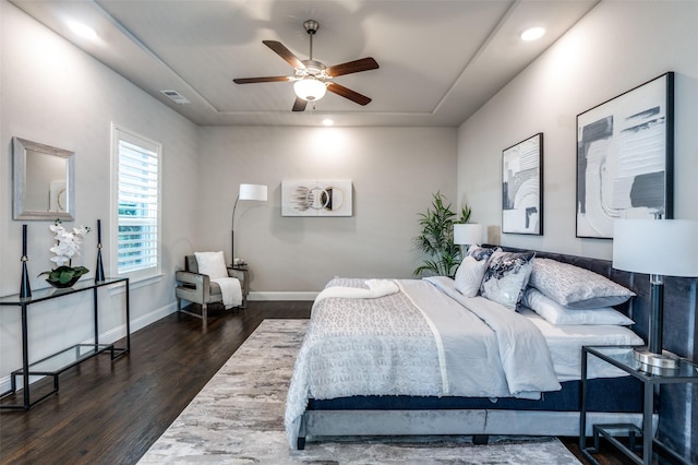 bedroom with visible vents, a raised ceiling, dark wood-style flooring, and baseboards