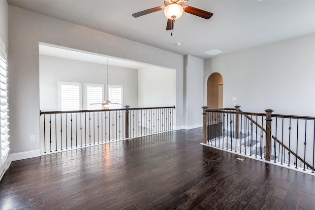 unfurnished room with arched walkways, a ceiling fan, baseboards, wood finished floors, and visible vents