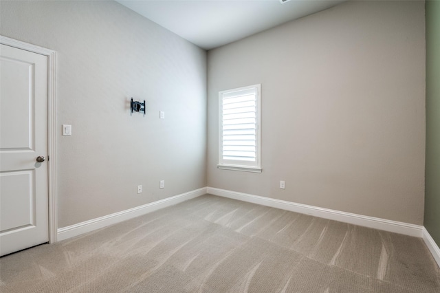 spare room with baseboards and light carpet