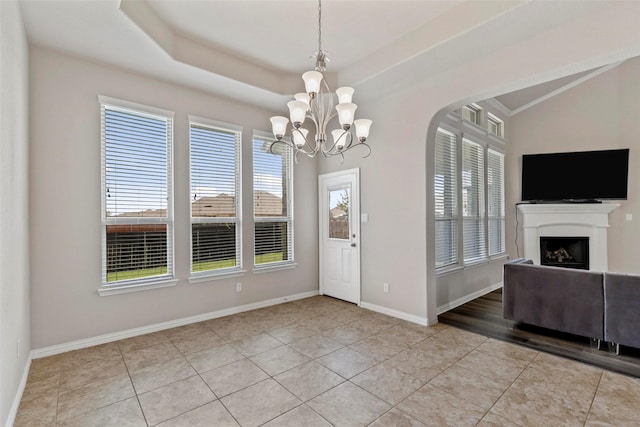 foyer entrance featuring an inviting chandelier, light tile patterned flooring, a fireplace, baseboards, and arched walkways