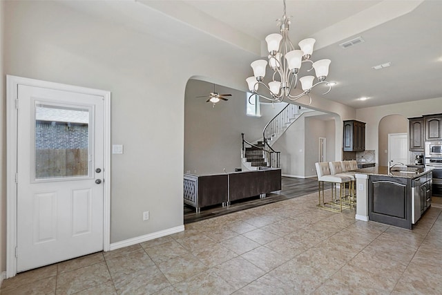 kitchen with visible vents, a sink, arched walkways, ceiling fan with notable chandelier, and stainless steel appliances