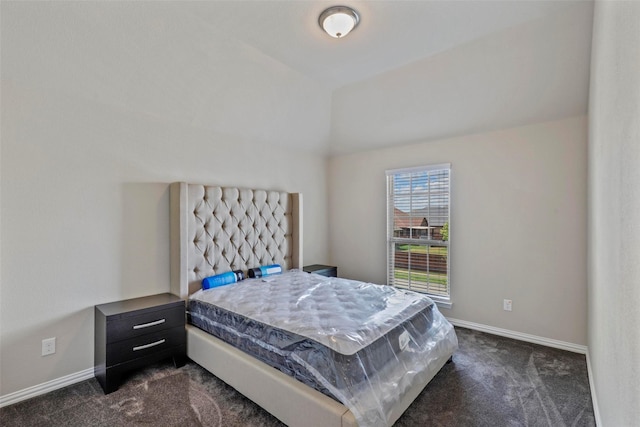 bedroom featuring baseboards, vaulted ceiling, and dark colored carpet