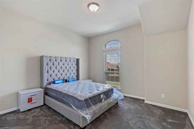 bedroom with baseboards and dark colored carpet