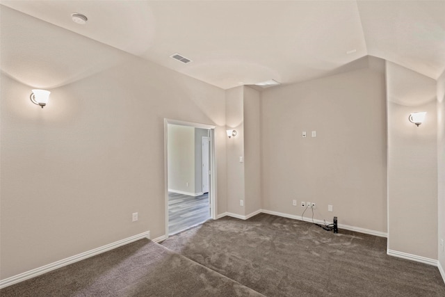 unfurnished room with visible vents, baseboards, dark carpet, and vaulted ceiling