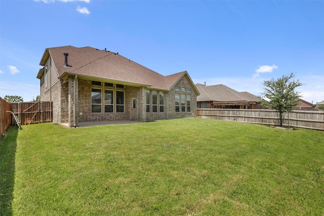 back of house with brick siding, a fenced backyard, a patio area, and a yard