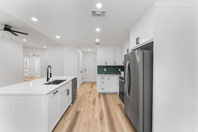 kitchen featuring appliances with stainless steel finishes, a sink, an island with sink, a ceiling fan, and visible vents