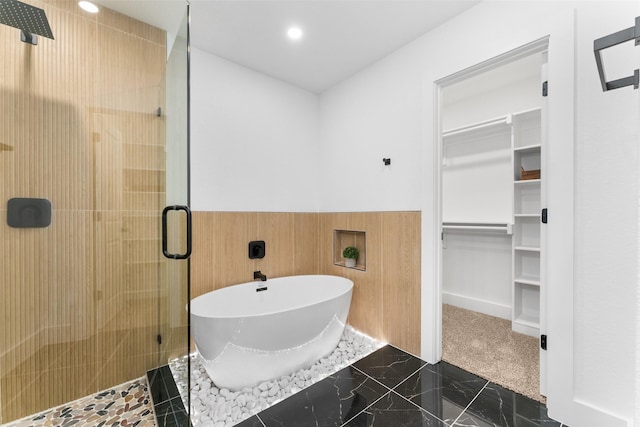 bathroom featuring a freestanding tub, wainscoting, a walk in closet, recessed lighting, and a stall shower