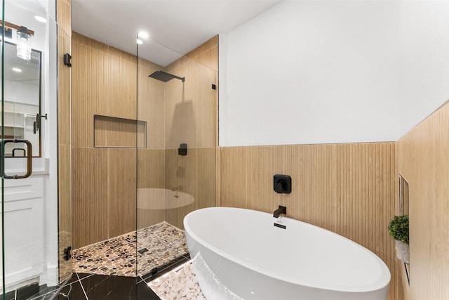 full bath with a wainscoted wall, a stall shower, and a soaking tub