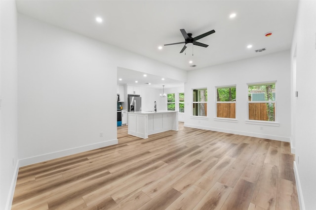 unfurnished living room featuring ceiling fan, a sink, light wood finished floors, recessed lighting, and baseboards