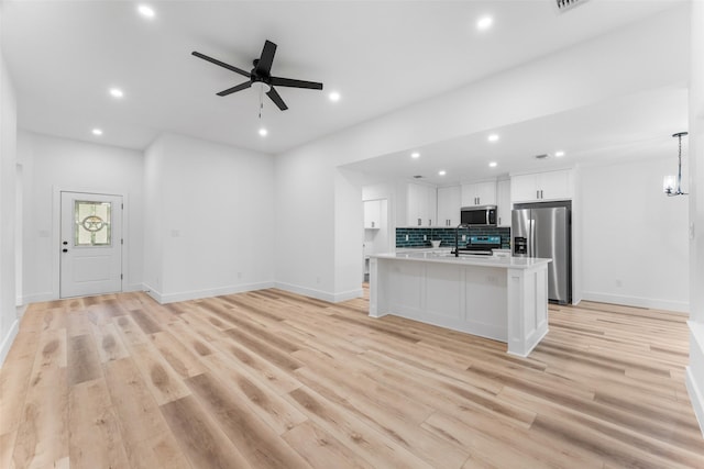 kitchen with tasteful backsplash, open floor plan, stainless steel appliances, recessed lighting, and white cabinetry