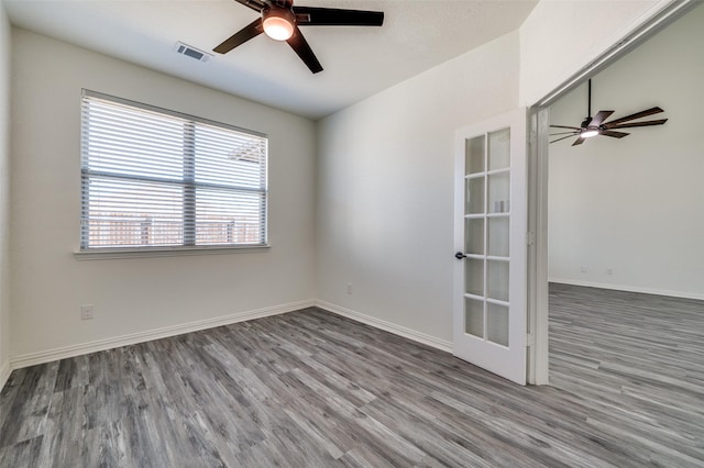 unfurnished room featuring ceiling fan, wood finished floors, and visible vents
