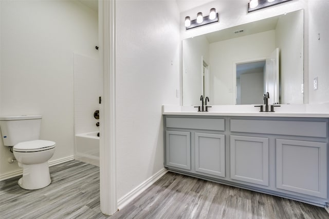 full bath featuring toilet, a sink, wood finished floors, and visible vents